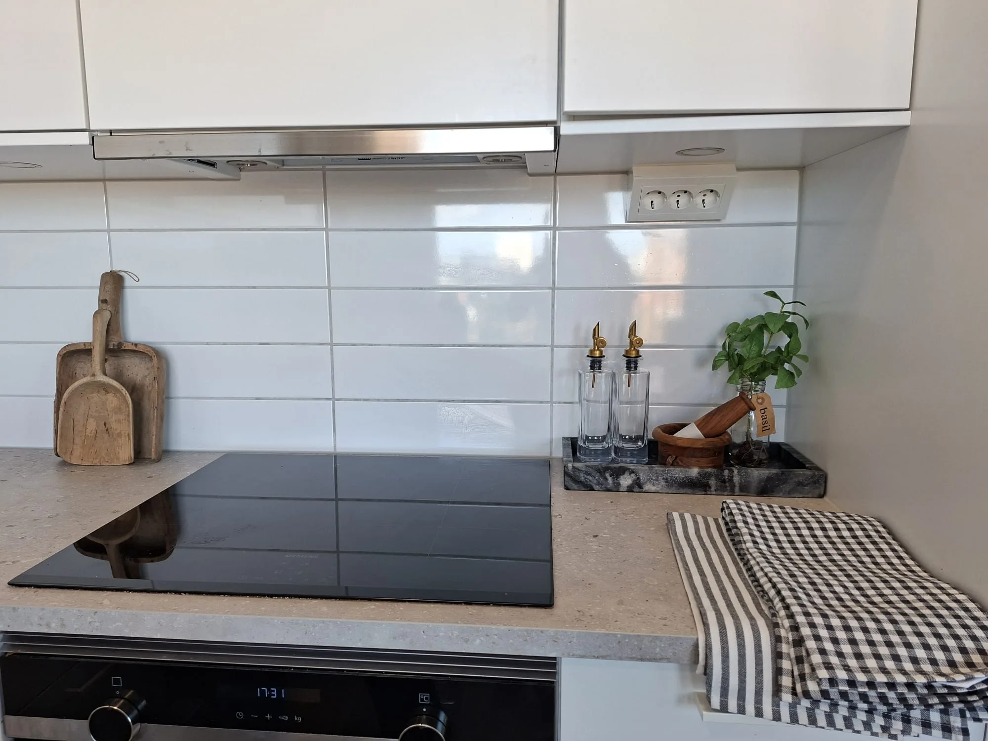 Köksdetalj med induktionshäll, skärbrädor och grönska – homestaging i Pedagogen Park, Mölndal | Viva Design