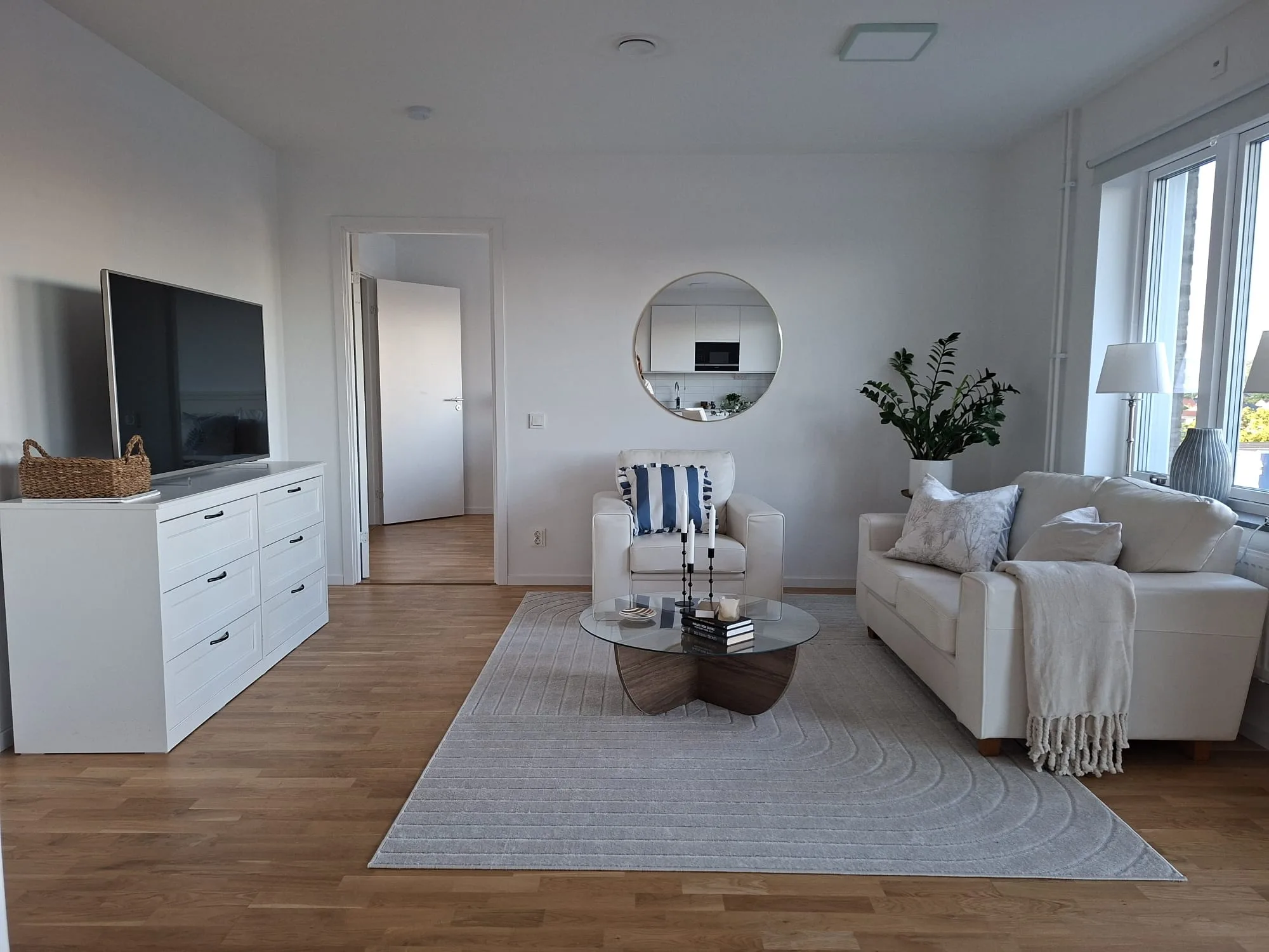 Stylat vardagsrum med ljus soffa, spegel och grönska – homestaging i Pedagogen Park, Mölndal | Viva Design